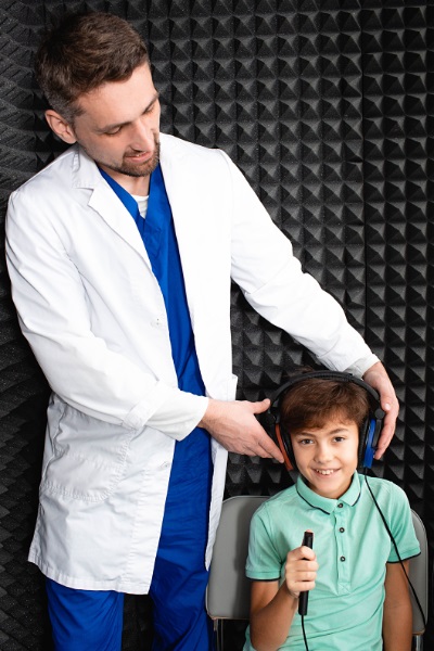Male doctor holding earphones on a child's head